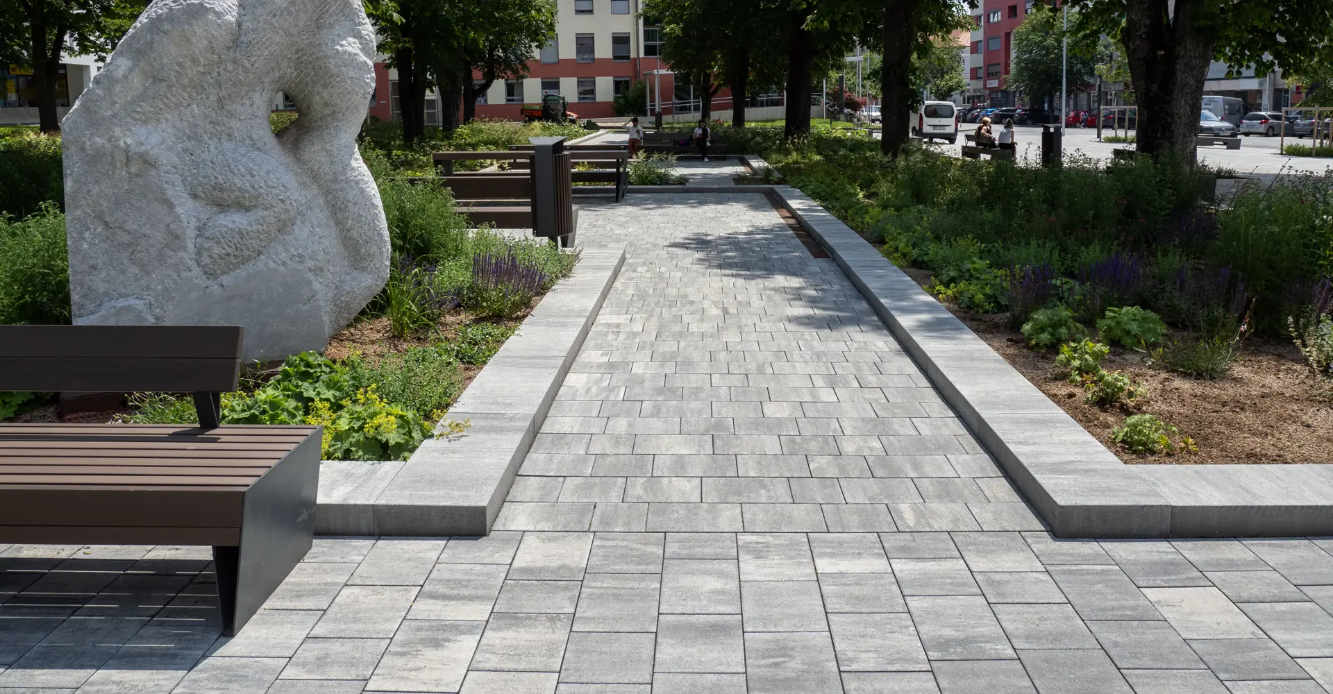 Weg mit Sitzbank und Steinskulptur im Stadtgarten Oberwart; Magnum und Arret B25 VG4 Pflastersteine granitgrau-schattiert, Friedl Steinwerke.
