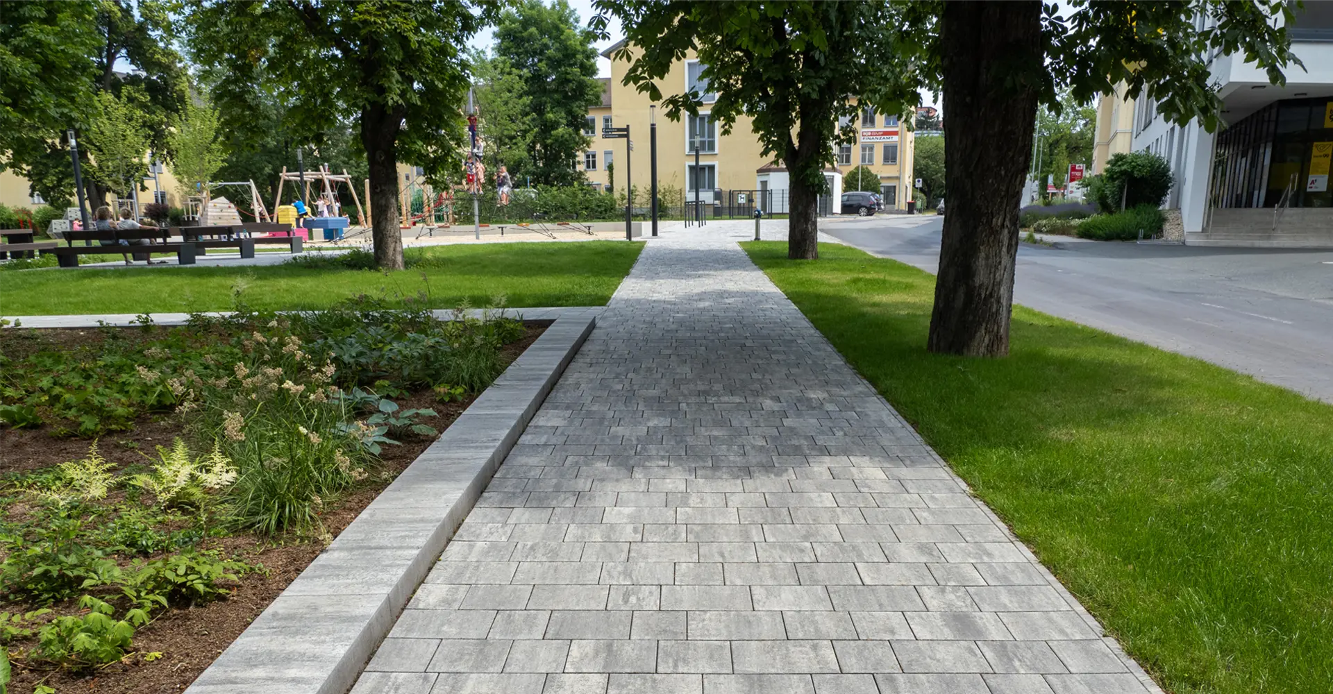 Weg im Stadtgarten Oberwart mit Arret B25 VG4 Kombipflaster granitgrau-schattiert zwischen Bäumen und Grünflächen, Friedl Steinwerke.