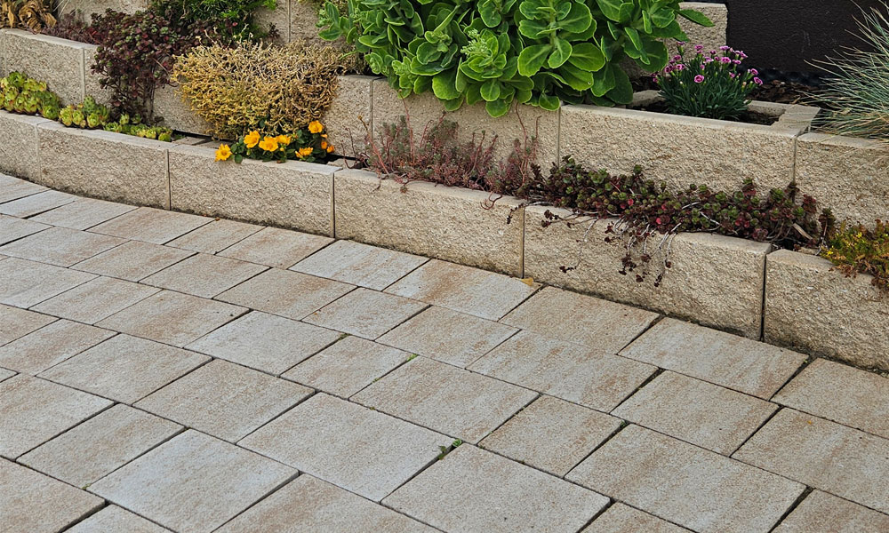 Faro Pflanzsteine kalkstein-schattiert von Friedl Steinwerke bilden eine gestufte Bepflanzungsmauer, davor verlegt das Piazza Pflaster im selben Farbton – gemeinsam eine harmonische Kombination. Faro Pflanzsteine kalkstein-schattiert von Friedl Steinwerke bilden eine gestufte Bepflanzungsmauer, davor verlegt das Piazza Pflaster im selben Farbton – gemeinsam eine harmonische Kombination.