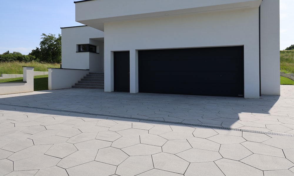 Kumo VG4 silbergrau-nuanciert Polygonplatte von Friedl Steinwerke verlegt in einer modernen Einfahrt mit markanter, unregelmäßiger Geometrie.