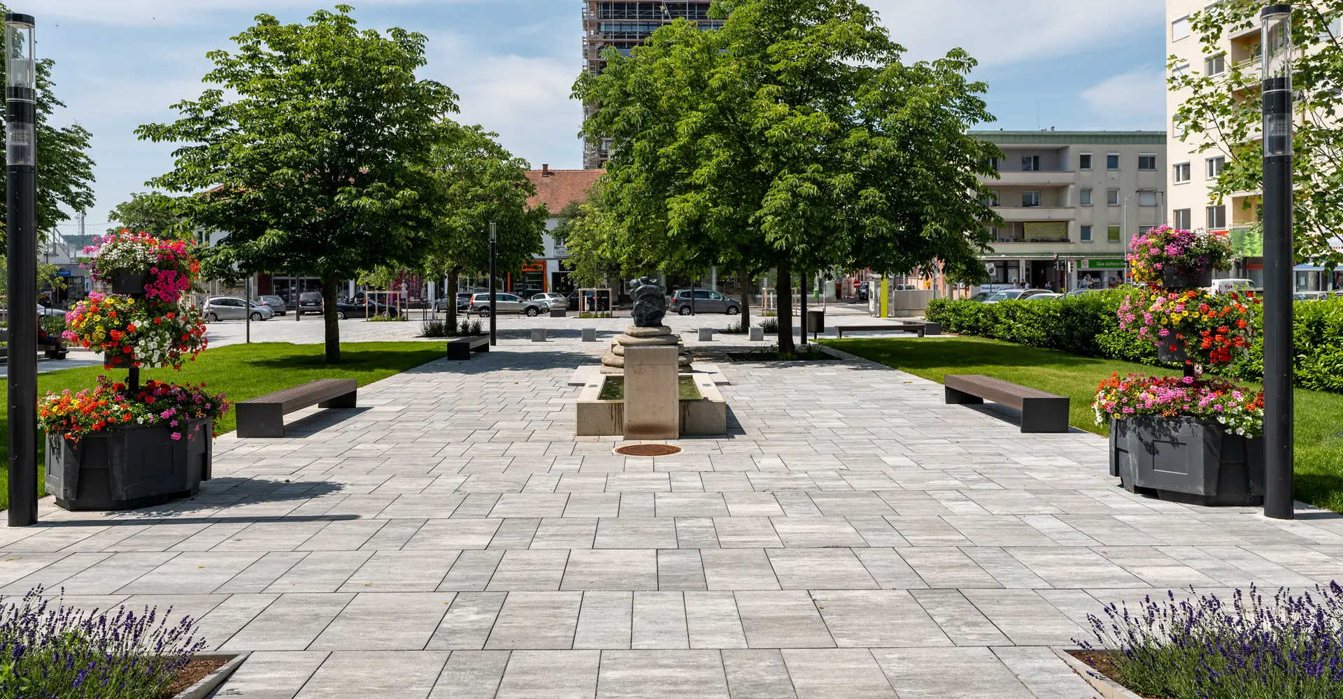 Stadtgarten Oberwart mit Magnum Platten granitgrau-schattiert, moderner Platz mit Bäumen und Blumen, Friedl Steinwerke.