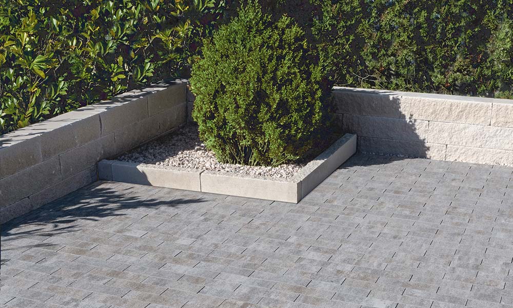 Sigma Riemchen basalt-schattiert kombiniert mit Mauerblock Momento 60 x 16 x 15 cm kreide als Mauer, Mauerblock Momento 60 x 24 x 7,5 cm kreide als Randeinfassung und Friedl Zierkies Dusty Champagne