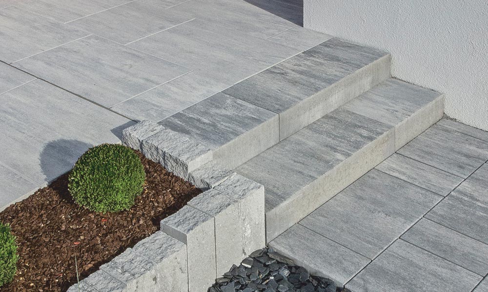 Linea Blockstufe 100 x 40 x 15 cm granitgrau-schattiert kombiniert mit Campus VG4 granitgrau-schattiert , Largo Terrassenplatte eisgrau-schattiert, Palisade Gutshof 3-seitig gespalten granitgrau-schattiert