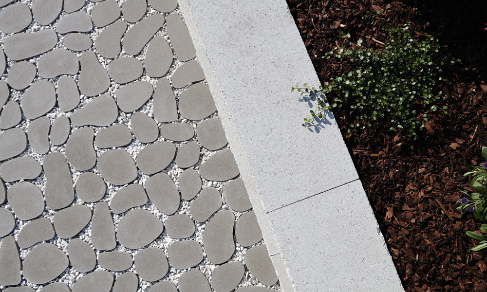 Rasenplatte Dribbs mit Kies befüllt und kombiniert mit Mauerblock Momento altweiß als Hochbeet Ansprechendes Sickerpflaster mit Pflanzen kombiniert von Friedl Steinwerke.