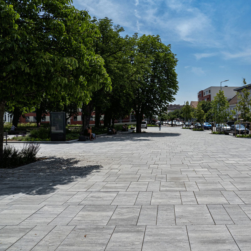 Stadtgarten Oberwart mit großzügiger Platzfläche und Baumreihe; Magnum granitgrau-schattiert, Friedl Steinwerke.