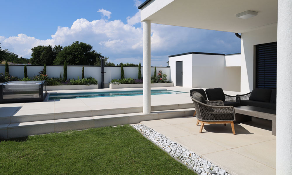 LIV quarzit von Friedl Steinwerke als Terrassenplatte rund um den Pool und im überdachten Lounge-Bereich – klare Linien und moderne Gartengestaltung.